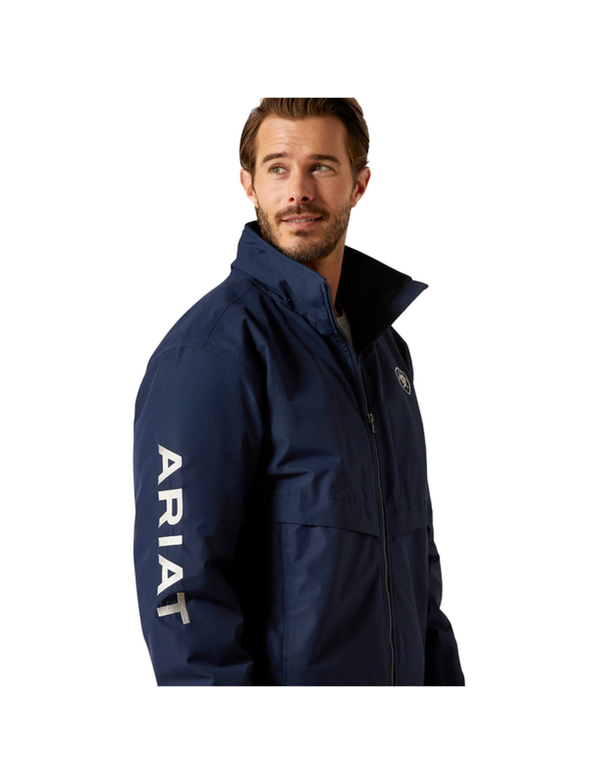 A man wearing a navy blue Ariat jacket, shown from the chest up in a side profile against a solid white background. The jacket features a high collar, a front zipper, and the brand name 'ARIAT' printed vertically in white on the left sleeve.